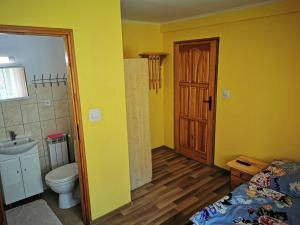 ein Bad mit einem WC, einem Waschbecken und einer Tür in der Unterkunft Pokoje nad strumykiem w Polanczyku tel 13- 469 -2257 in Polańczyk