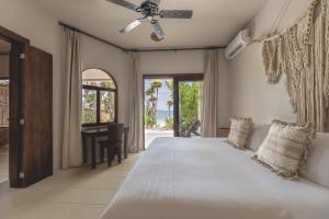 a bedroom with a large white bed with a ceiling fan at NEST Tulum in Tulum +166 photos