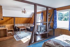 a room with wooden walls and a living room with a tv at Vila Poilsis Nidoje in Nida