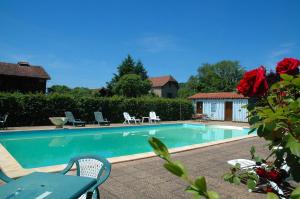 a swimming pool with chairs and a table and roses at Le Relais des 5 Chateaux in Vézac