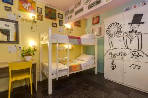 um quarto com beliches, uma secretária e uma cadeira. em Fit Hostel no Recife