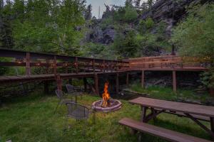 a fire pit in a yard with benches and a bridge at Harney Camp Cabins in Hill City