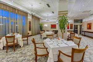 uma sala de jantar com mesas e cadeiras brancas em Grand Hotel Pomorie em Pomorie