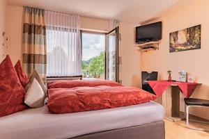 a hotel room with a red bed and a window at Landhaus Heimisch Bed & Breakfast in Geisfeld