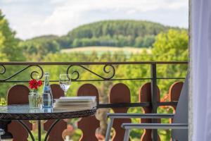 een tafel met een glas wijn op een balkon met uitzicht bij Landhaus Heimisch Bed & Breakfast in Geisfeld