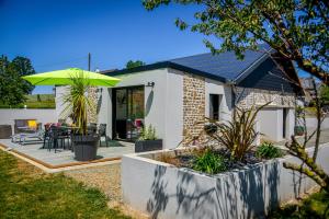een huis met een patio met een groene parasol bij détente et confort - gite baie bocage in Sartilly