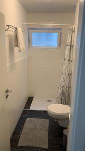 biała łazienka z toaletą i oknem w obiekcie Süßes Zimmer im Souterrain w mieście Frensdorf