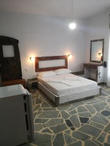 1 dormitorio con cama y espejo en la pared en Arleta's Sunny Guesthouse en Prinos