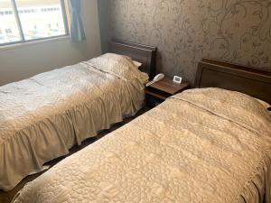 Un dormitorio con 2 camas y un teléfono en una mesa. en Sado - Hotel - Vacation STAY 82496, en Sado