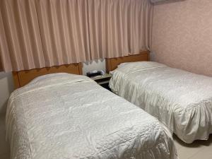 2 Betten in einem Hotelzimmer mit Vorhängen und Bettröcken in der Unterkunft Sado - Hotel - Vacation STAY 82476 in Sado