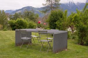 une table et des chaises dans une cour avec des montagnes en arrière-plan dans l'établissement Grava - Ferienwohnung für max. 2 Personen, à Laax