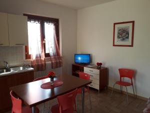 uma cozinha com uma mesa e cadeiras e uma televisão em Residence Ai Campi Da Golf Saturnia em Saturnia