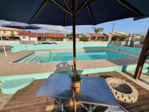 una mesa con sombrilla junto a la piscina en 01 - Casa Praia da Pinheira pousada, en Palhoça