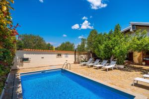 a swimming pool with lounge chairs next to a house at Olive House Zadar in Zadar