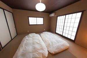 a large bed in a room with two windows at SyukuyaYokohama Main Building 1F - Vacation STAY 82573 in Kitagatamachi