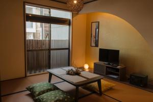 a living room with a table and a tv at SyukuyaYokohama Main Building 1F - Vacation STAY 82573 in Kitagatamachi