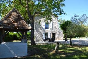 una casa de piedra con un cenador frente a ella en Gîte des Magnolias, en Nérac