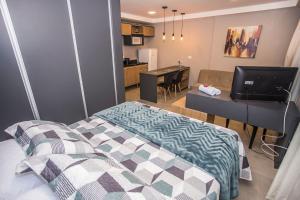 een slaapkamer met een bed, een bureau en een keuken bij Studio Andar Alto e Face Norte - ALL1611 in Curitiba