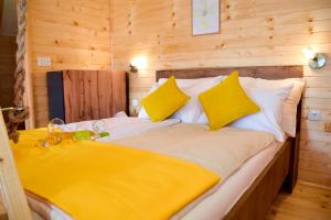 a large bed with yellow pillows in a wooden room at Cottage Lana in Jajce
