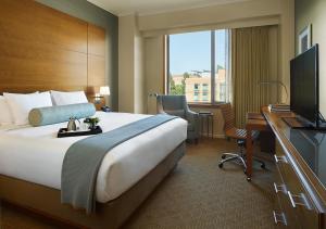 ロサンゼルスにあるLuskin Hotelのベッド、デスク、テレビが備わるホテルルームです。