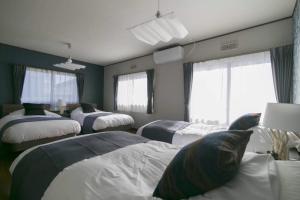 1 dormitorio con 3 camas y 2 ventanas en Minamitsuru-gun - House - Vacation STAY 82499, en Fujikawaguchiko