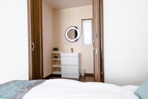 1 dormitorio con cama blanca y espejo en Minamitsuru-gun - House - Vacation STAY 82504, en Fujikawaguchiko