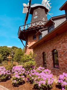 un edificio de ladrillo con un molino de viento y flores púrpuras en Oldenburger Mühle, en Oldenburg