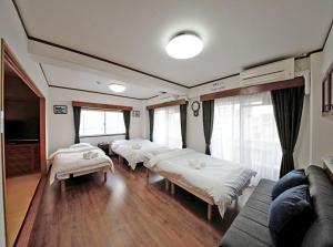 een kamer met 4 bedden, een bank en ramen bij La Foret Fujimi - Vacation STAY 83089 in Hiroshima