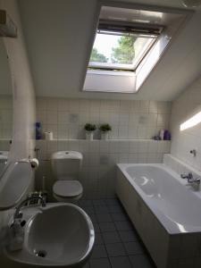 a bathroom with a tub and a toilet and a sink at de Duinroos in Oostkapelle