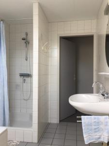 een badkamer met een bad, een wastafel en een douche bij de Duinroos in Oostkapelle