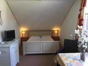 a bedroom with a bed and a desk with a television at de Duinroos in Oostkapelle