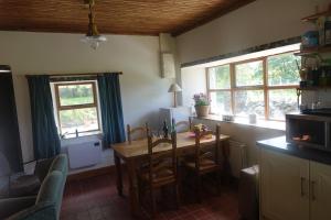a kitchen with a table and chairs and windows at Bell Cottage in Gortahork