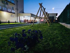 einen Spielplatz im Garten mit blauen Blumen im Gras in der Unterkunft Casa Barina Costinești in Costinești