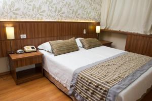 Un dormitorio con una cama y un teléfono en una mesa. en LEON PARK HOTEL e CONVENÇÕES - Melhor Custo Benefício, en Campinas