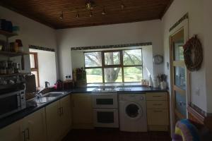 a kitchen with a washing machine and a window at Bell Cottage in Gortahork