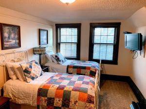 a bedroom with two beds and a tv and windows at Iowa House Historic Inn in Ames