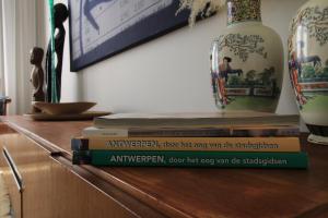 einen Stapel Bücher, die auf einem Regal mit einer Vase sitzen in der Unterkunft The Soul Antwerp in Antwerpen