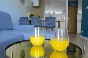 two glasses of orange juice sitting on a glass table at Arkadia Kołobrzeg in Kołobrzeg