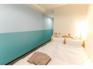 - une chambre dotée d'un lit avec des draps blancs et des murs bleus dans l'établissement SERENDIP HOTEL GOTO - Vacation STAY 82392, à Goto