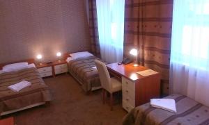 a small room with two beds and a desk with a desk at Hotel & SPA Odeon in Boguchwała