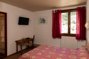 a bedroom with a bed and a table and a window at Hôtel de la Mairie in LʼArgentière-la-Bessée