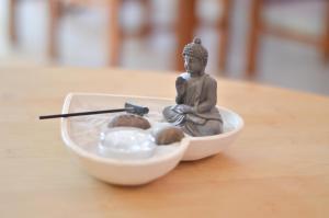 Una piccola statua di Buddha seduta in una ciotola d'acqua di Apartamento Stª Eulália Deluxe by Umbral ad Albufeira