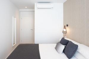 ein Schlafzimmer mit einem weißen Bett mit blauen Kissen in der Unterkunft CONCHEIROS 5 APARTAMENTOS TURISTICOS in Santiago de Compostela