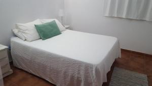 Una cama blanca con una almohada verde encima. en Casa Baro, en Zahora