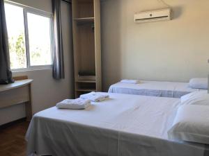 Habitación con 2 camas y toallas. en Hotel Nunes, en Curitiba