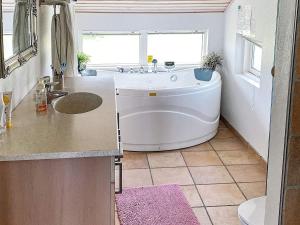 a bathroom with a tub and a sink at 7 person holiday home in R dby in Rødby