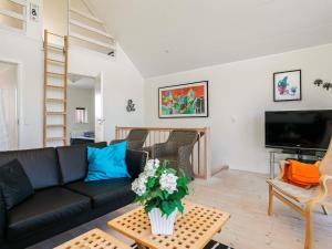 a living room with a black couch and a tv at 6 person holiday home in Løkken-By Traum in Løkken