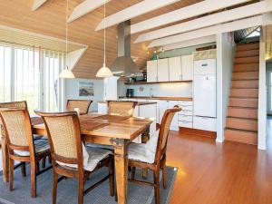 kuchnia i jadalnia z drewnianym stołem i krzesłami w obiekcie 8 person holiday home in L kken w mieście Løkken