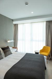 ein Schlafzimmer mit einem großen Bett und einem gelben Stuhl in der Unterkunft CONCHEIROS 5 APARTAMENTOS TURISTICOS in Santiago de Compostela