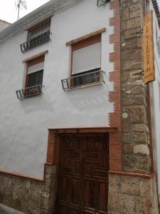 een wit gebouw met een houten deur en ramen bij Habitacion tienda de felipe EL DESPACHO in Pontones